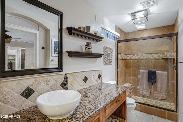 full bath with toilet, visible vents, a shower stall, ceiling fan, and vanity