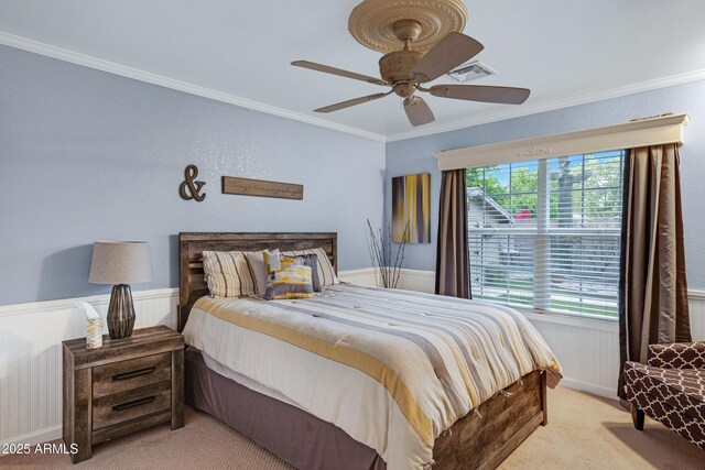 carpeted bedroom with a ceiling fan, ornamental molding, a wainscoted wall, and visible vents