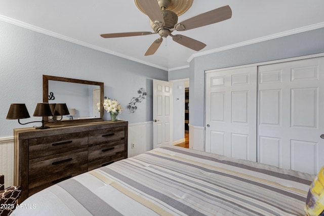 bedroom with a closet, crown molding, ceiling fan, and wainscoting