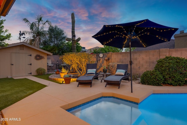 view of swimming pool with a fenced in pool, a fenced backyard, an outbuilding, a patio, and a storage unit