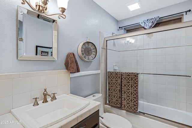 bathroom with toilet, a notable chandelier, vanity, and combined bath / shower with glass door