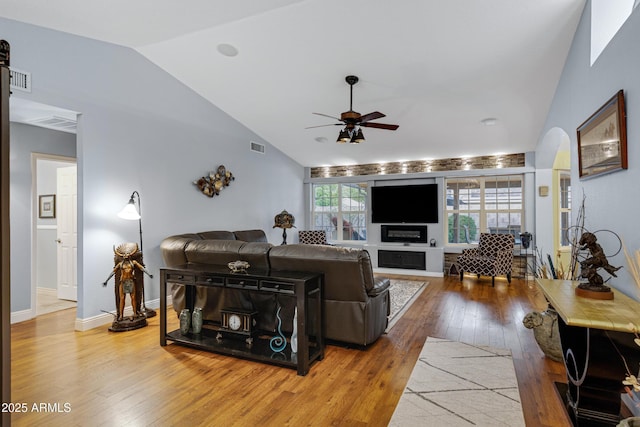 living area featuring hardwood / wood-style floors, ceiling fan, baseboards, lofted ceiling, and visible vents