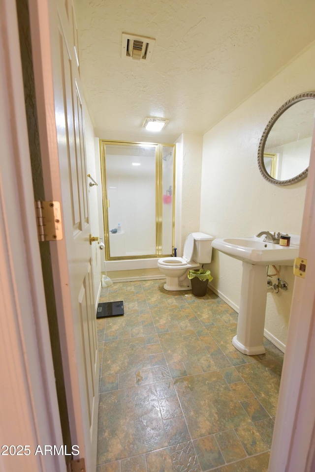 1219 E Avenida Isabela, Casa Grande, AZ 85122 - bathroom with baseboards, toilet, a stall shower, stone finish flooring, and a textured ceiling