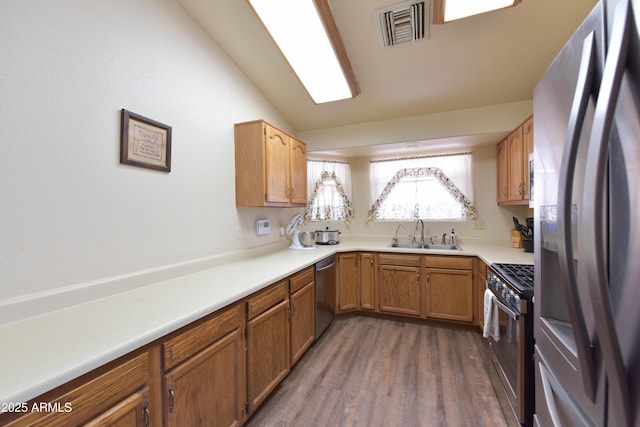 1219 E Avenida Isabela, Casa Grande, AZ 85122 - kitchen with appliances with stainless steel finishes, a sink, dark wood-style flooring, vaulted ceiling, and brown cabinets
