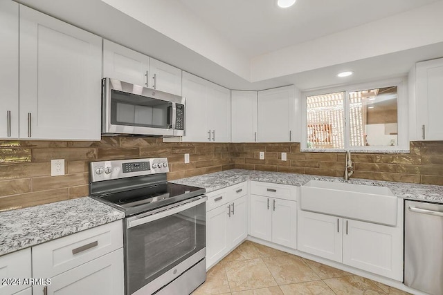 kitchen featuring white cabinetry, sink, stainless steel appliances, tasteful backsplash, and light stone counters