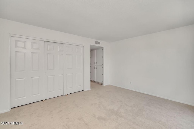 unfurnished bedroom featuring light carpet and a closet