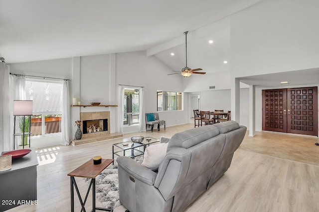 living room with high vaulted ceiling, light hardwood / wood-style flooring, ceiling fan, a fireplace, and beam ceiling