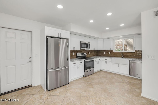 kitchen with tasteful backsplash, white cabinetry, sink, and stainless steel appliances