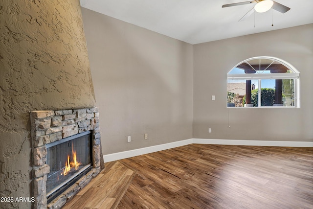 5345 E Mclellan Rd Unit 123, Mesa, AZ 85205 - unfurnished living room featuring wood finished floors, a stone fireplace, a ceiling fan, and baseboards