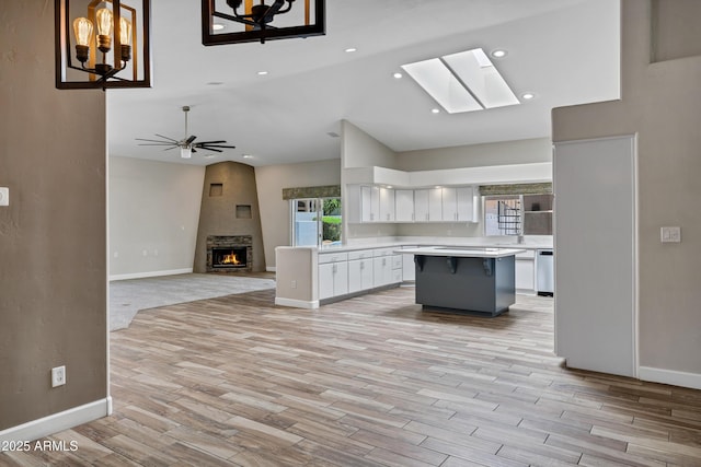 5345 E Mclellan Rd Unit 123, Mesa, AZ 85205 - kitchen with a lit fireplace, white cabinets, light countertops, a center island, and baseboards