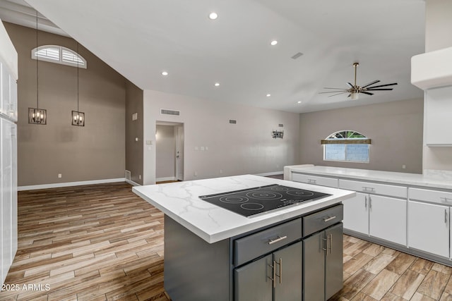 5345 E Mclellan Rd Unit 123, Mesa, AZ 85205 - kitchen with black electric cooktop, light wood-style floors, a kitchen island, white cabinets, and lofted ceiling