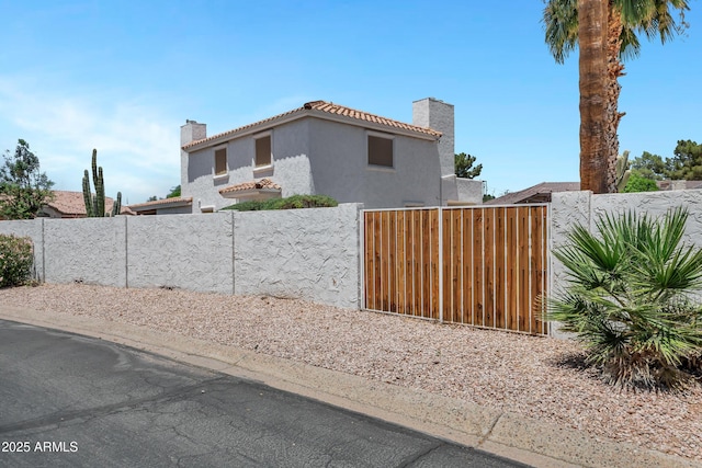 5345 E Mclellan Rd Unit 123, Mesa, AZ 85205 - view of property exterior with a chimney, stucco siding, a gate, and a tiled roof