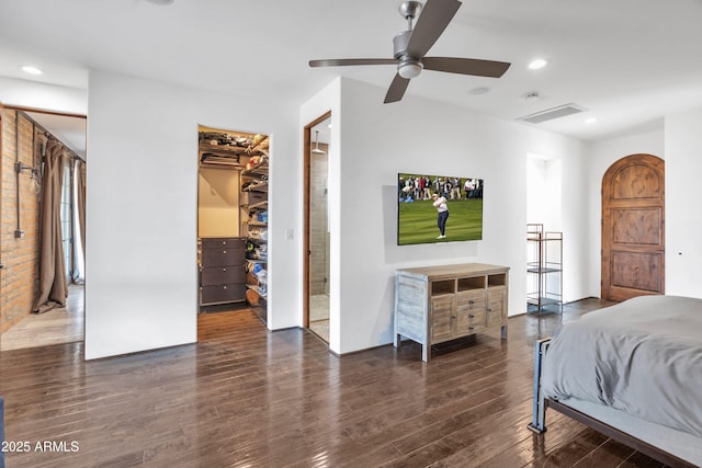 bedroom featuring a walk in closet, dark wood-type flooring, and ceiling fan