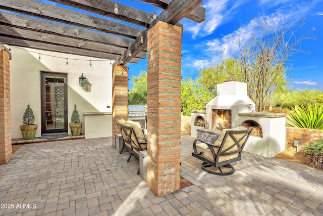 view of patio / terrace with a warm lit fireplace, exterior kitchen, and a pergola