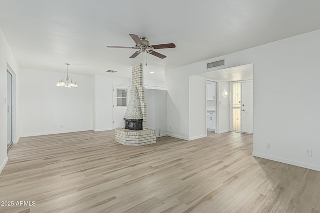 6051 E Ensenada St, Mesa, AZ 85205 - unfurnished living room featuring a wood stove, ceiling fan, a chandelier, light wood-type flooring, and baseboards