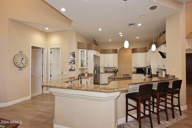 kitchen featuring light wood-type flooring, hanging light fixtures, kitchen peninsula, and a kitchen breakfast bar