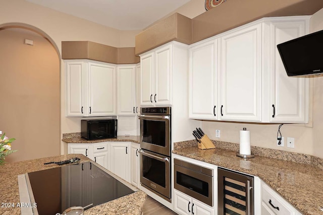 kitchen with white cabinetry, wine cooler, black appliances, and light stone countertops