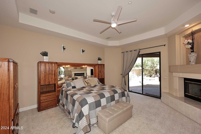 carpeted bedroom featuring a tray ceiling, access to outside, and ceiling fan