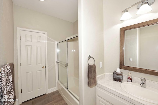 bathroom with bath / shower combo with glass door, hardwood / wood-style floors, and vanity