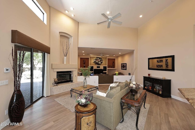 living room with light hardwood / wood-style floors, a towering ceiling, and ceiling fan