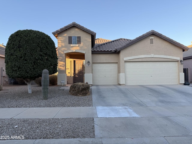 view of front of home with a tile roof, driveway, an attached garage, and stucco siding