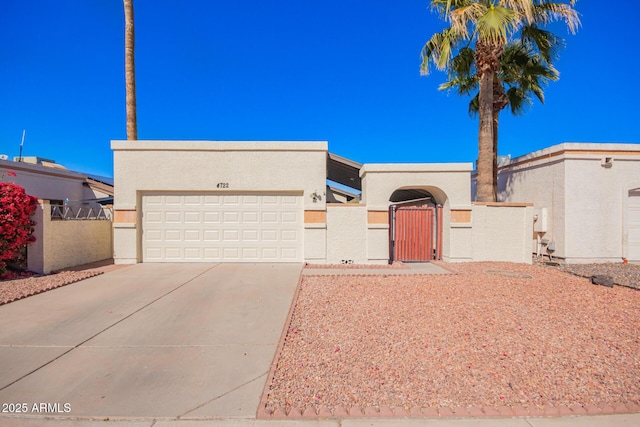 view of front of home with a fenced front yard, stucco siding, concrete driveway, an attached garage, and a gate