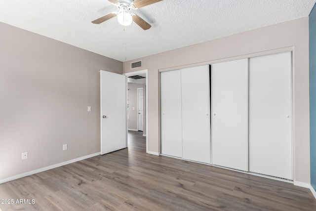 unfurnished bedroom with a textured ceiling, wood finished floors, and visible vents