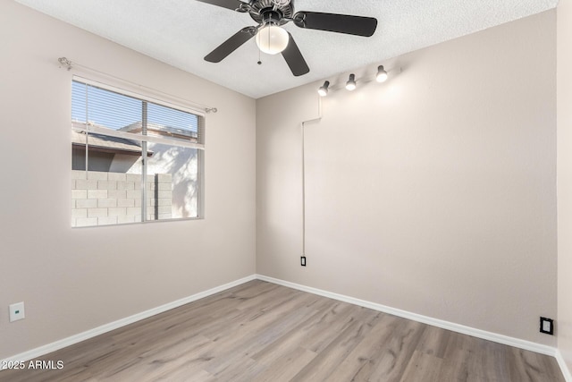 empty room featuring baseboards, ceiling fan, a textured ceiling, and light wood-style floors