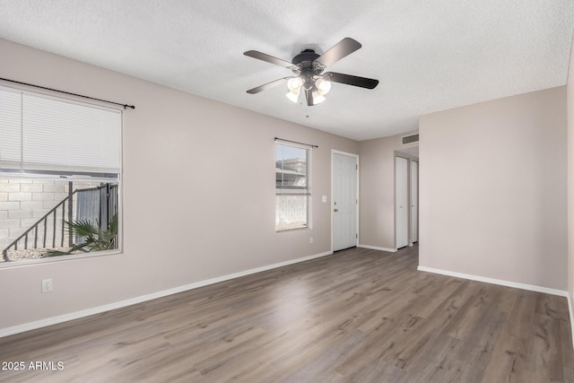 empty room with visible vents, baseboards, a ceiling fan, wood finished floors, and a textured ceiling