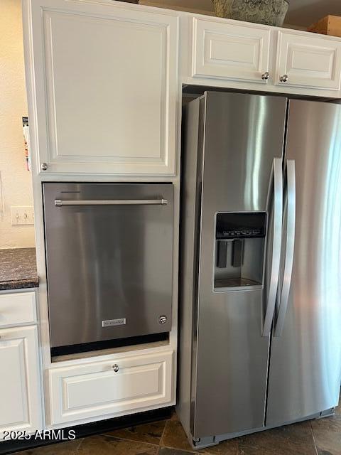 kitchen featuring dark stone counters, stainless steel fridge with ice dispenser, and white cabinets