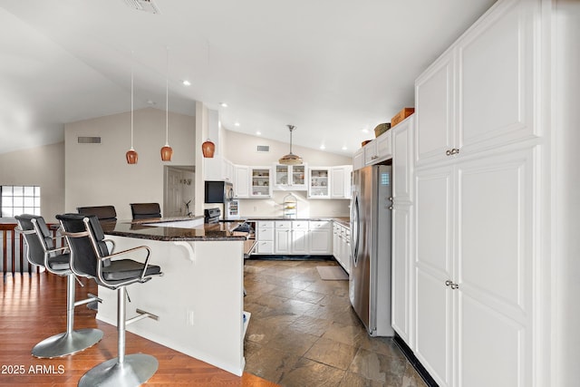 kitchen featuring electric range oven, white cabinetry, a breakfast bar area, stainless steel fridge, and hanging light fixtures