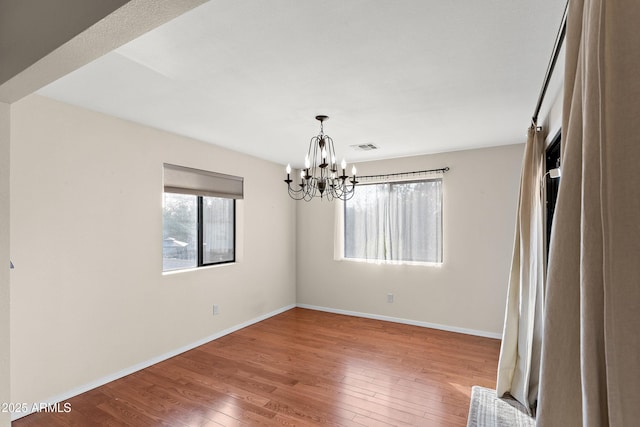 empty room featuring hardwood / wood-style flooring and a notable chandelier