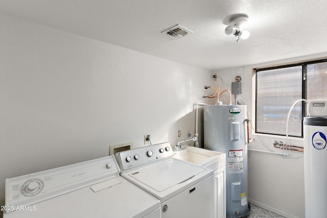 laundry area with water heater, washing machine and clothes dryer, and a textured ceiling