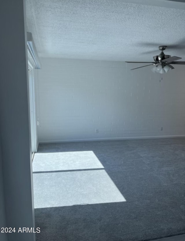 carpeted spare room featuring ceiling fan and a textured ceiling