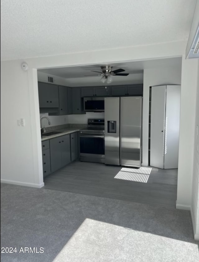 kitchen with carpet flooring, gray cabinetry, ceiling fan, sink, and stainless steel appliances