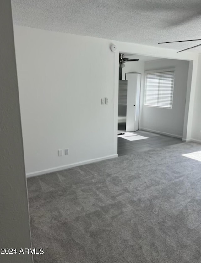 carpeted empty room with ceiling fan and a textured ceiling