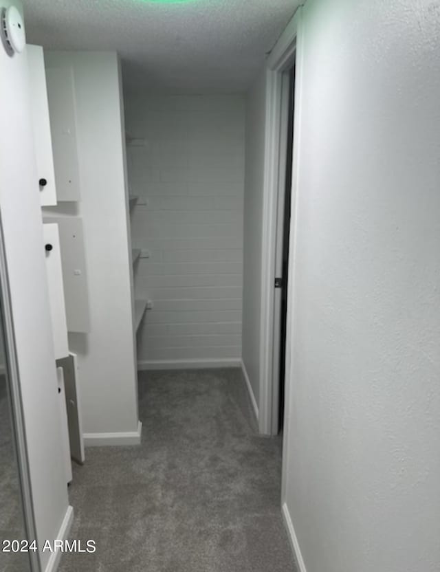 hall featuring dark carpet and a textured ceiling