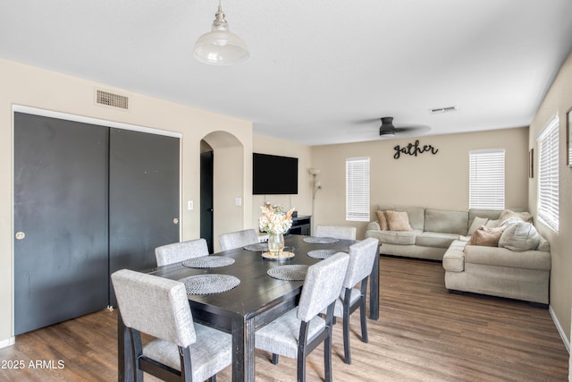 dining room with visible vents, arched walkways, wood finished floors, and a ceiling fan