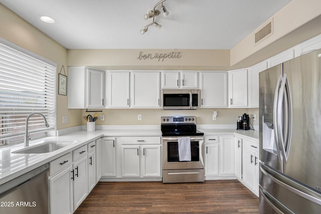 kitchen with visible vents, a sink, dark wood-type flooring, white cabinets, and appliances with stainless steel finishes