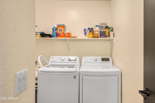 washroom with laundry area, washer and dryer, and a textured wall