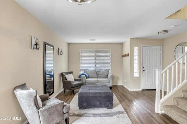 living area with visible vents, baseboards, wood finished floors, and stairs