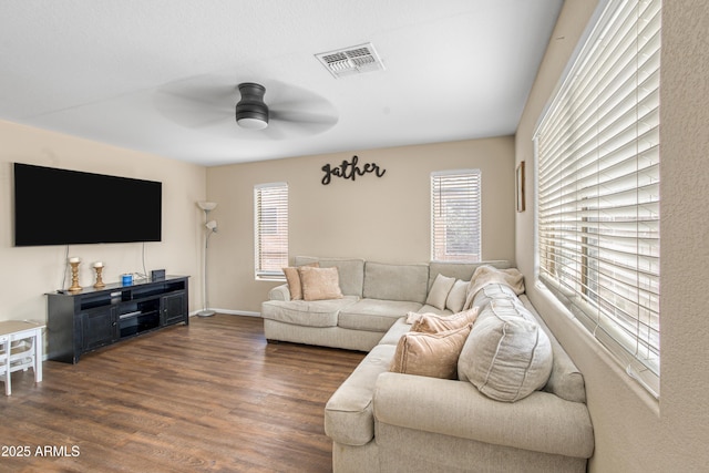 living area with a wealth of natural light, visible vents, wood finished floors, and ceiling fan