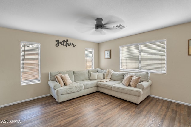 living area featuring dark wood finished floors, baseboards, visible vents, and ceiling fan