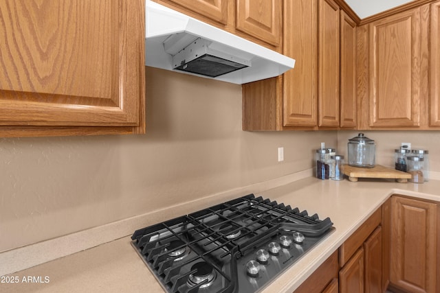 7145 E Cuernavaco Way, Gold Canyon, AZ 85118 - kitchen with under cabinet range hood, brown cabinets, stainless steel gas stovetop, and light countertops