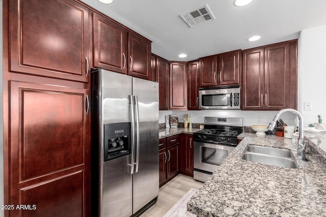 kitchen featuring light stone countertops, sink, light hardwood / wood-style flooring, and appliances with stainless steel finishes