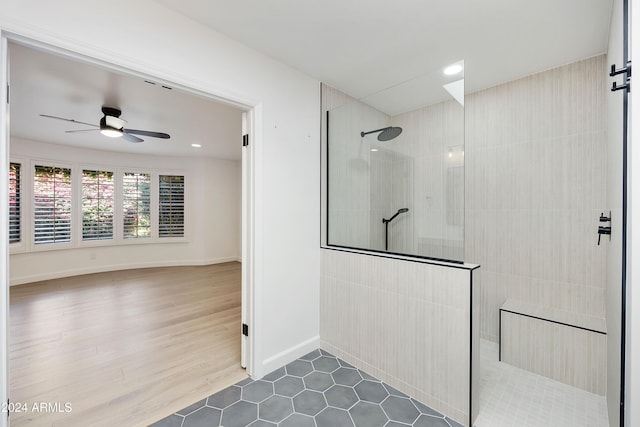 bathroom featuring a tile shower, ceiling fan, and wood-type flooring