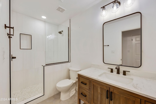 bathroom with tiled shower, tile patterned floors, vanity, and toilet