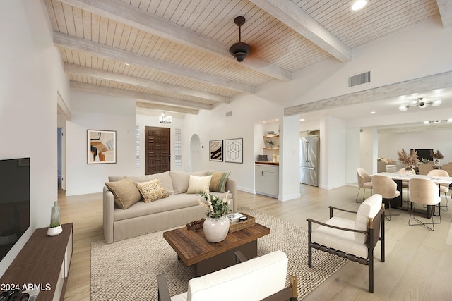 living room with beamed ceiling, ceiling fan with notable chandelier, light hardwood / wood-style floors, and wood ceiling