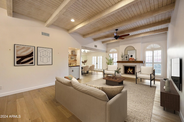 living room with beamed ceiling, ceiling fan, light hardwood / wood-style floors, and wood ceiling