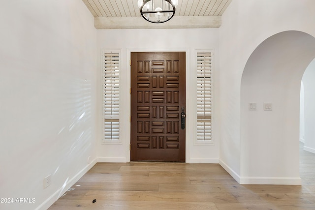 foyer featuring beam ceiling, light hardwood / wood-style flooring, wood ceiling, and an inviting chandelier